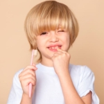 niño rubio con cepillo de dientes - agenesia dental infantil