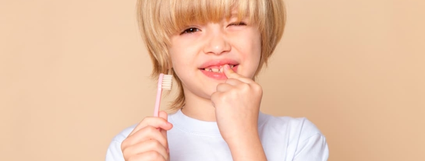 niño rubio con cepillo de dientes - agenesia dental infantil