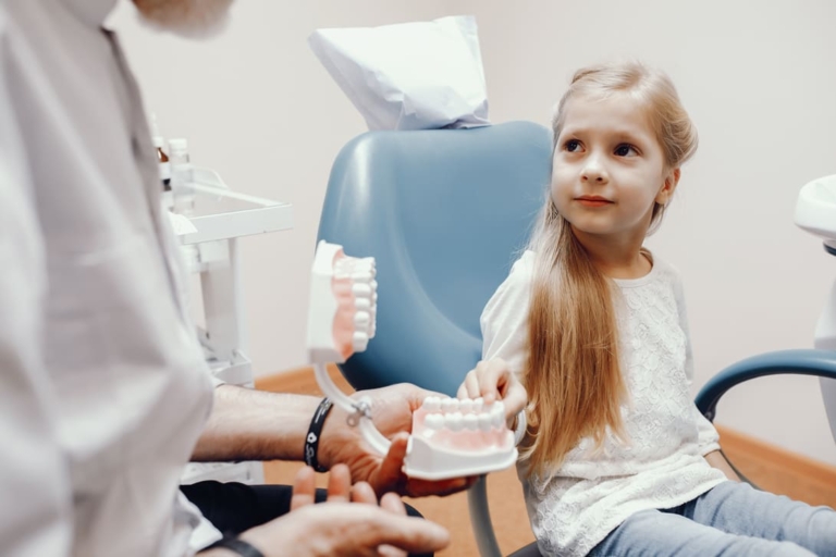 niña rubia en una revisión en el dentista - desmineralización dental en niños