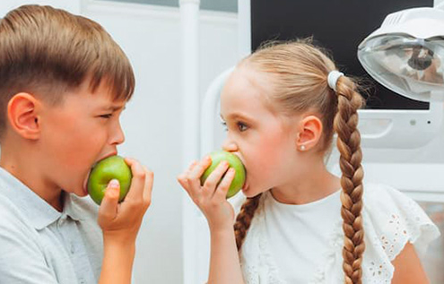 niño y niña comiendo manzana