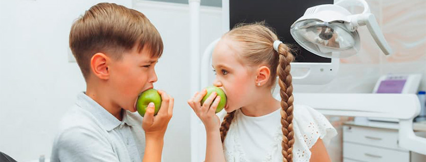 niño y niña comiendo manzana
