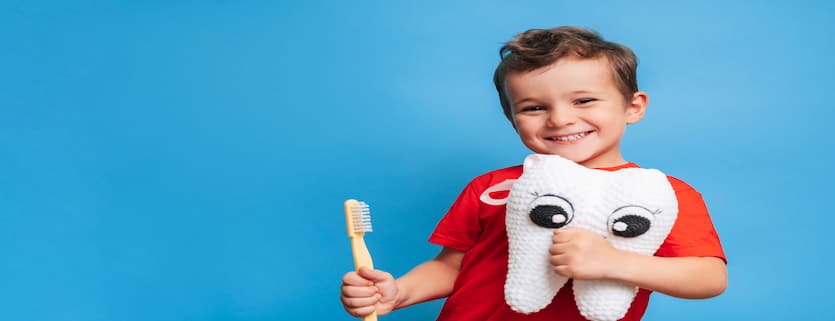 Niño feliz con cepillo de dientes y un peluche de un diente