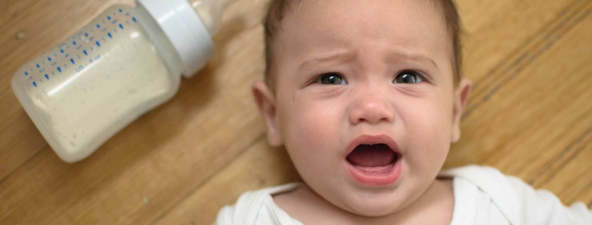 Bebé con síndrome del biberón tumbado en suelo