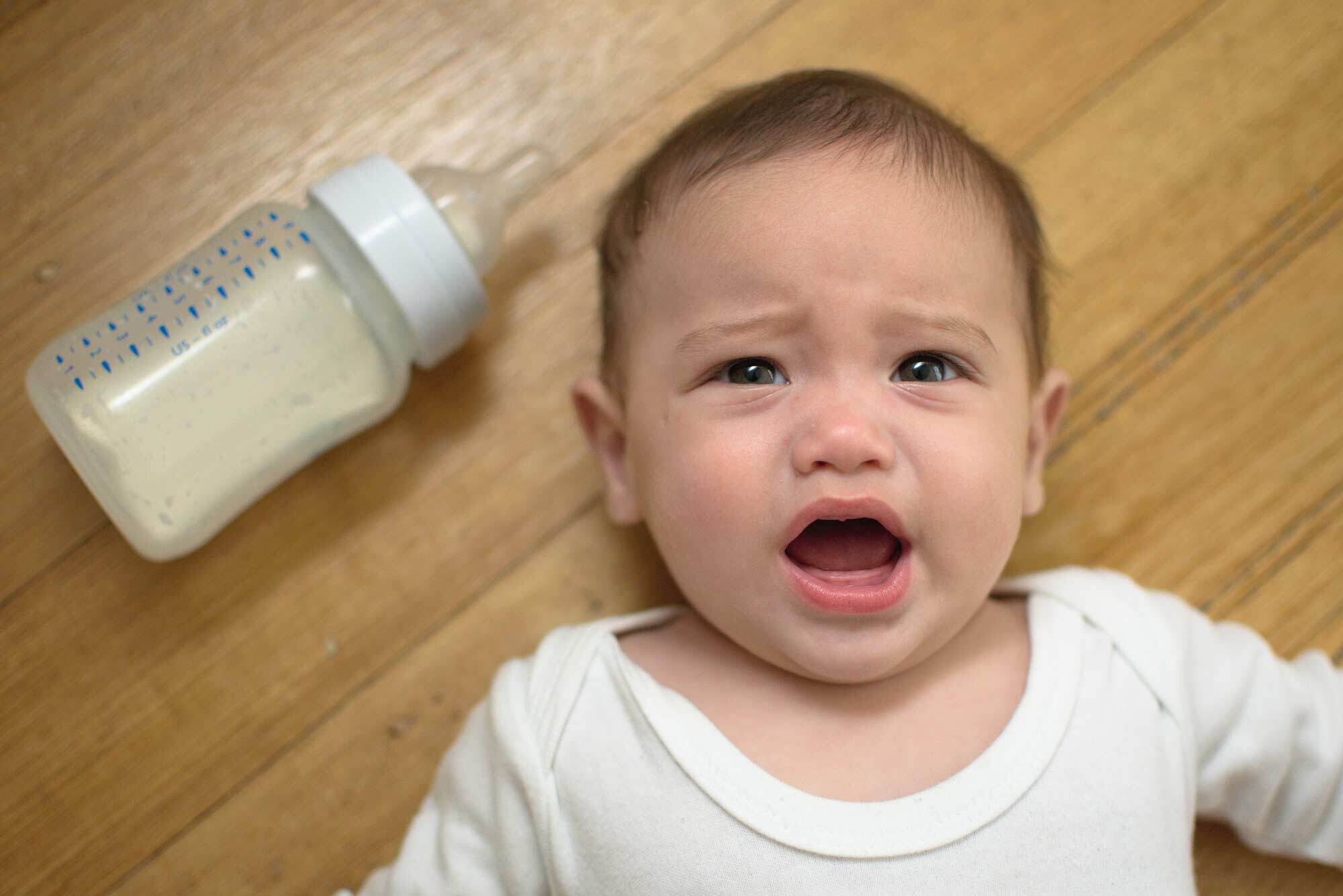 Bebé con síndrome del biberón tumbado en suelo