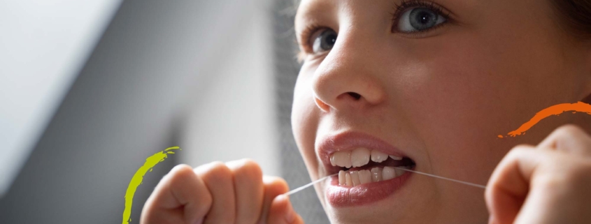 niña limpiándose los dientes con hilo dental