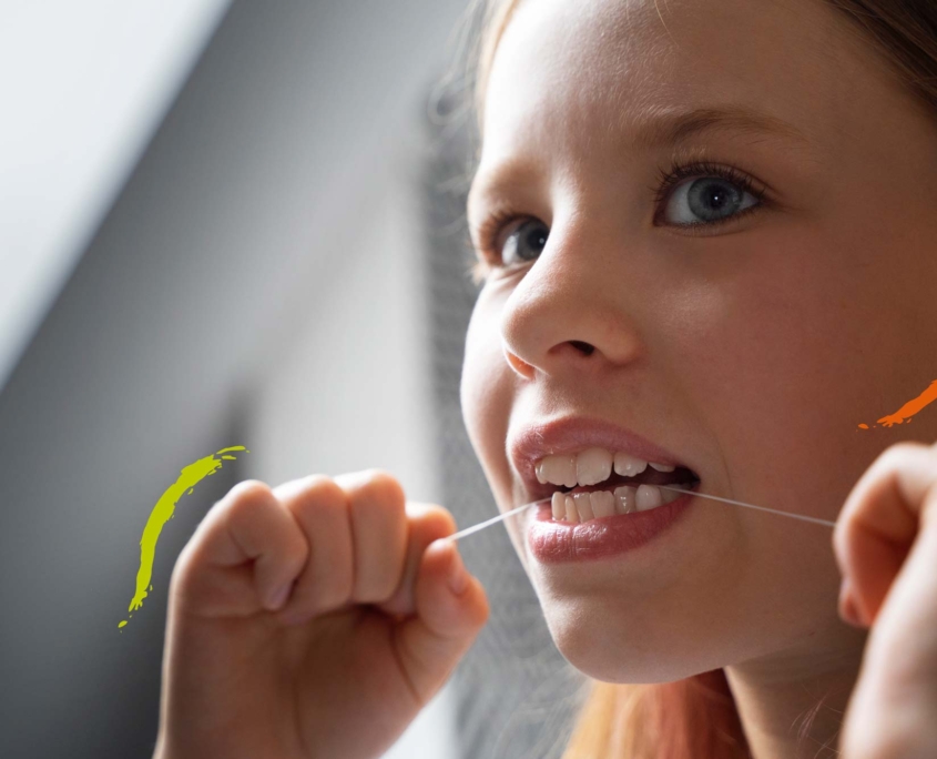 niña limpiándose los dientes con hilo dental