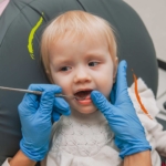 Bebé en la silla del dentista mientras el revisan los dientes