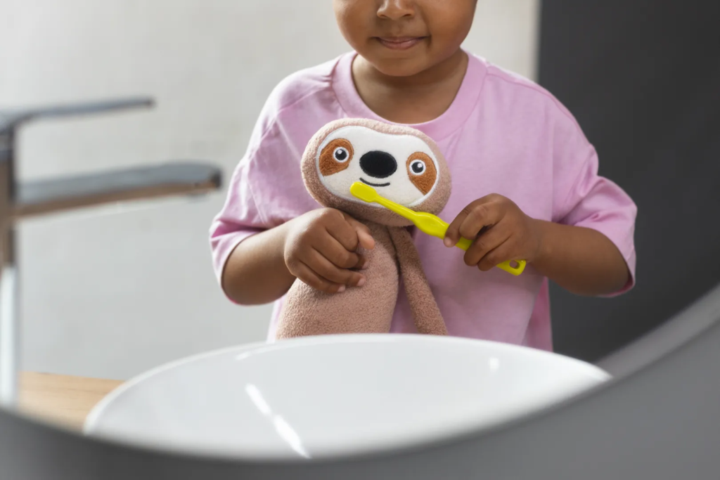 Niña con un peluche jugando a lavarle los dientes