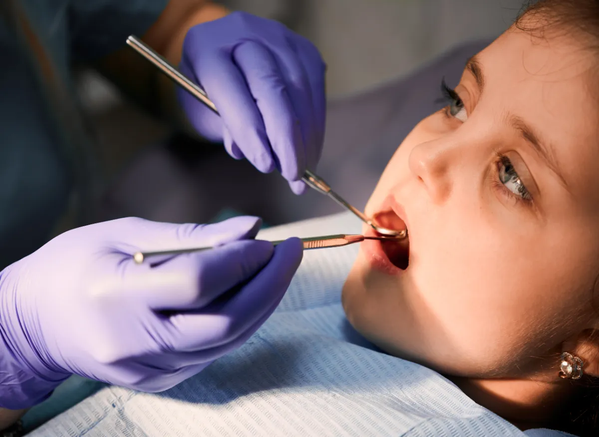 Odontopediatra revisando los dientes de una niña en la consulta dental